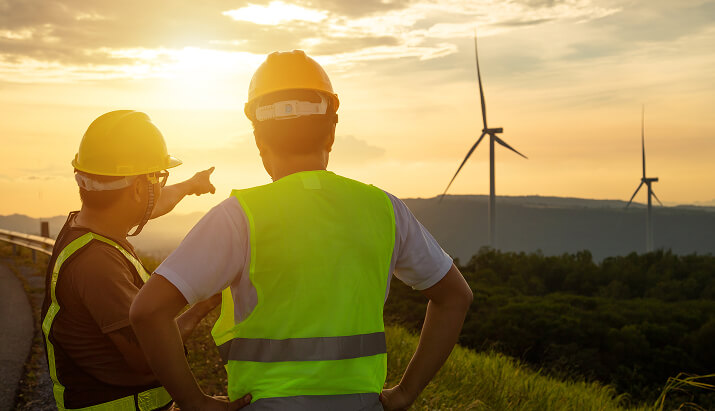 workers pointing at turbines in the distance